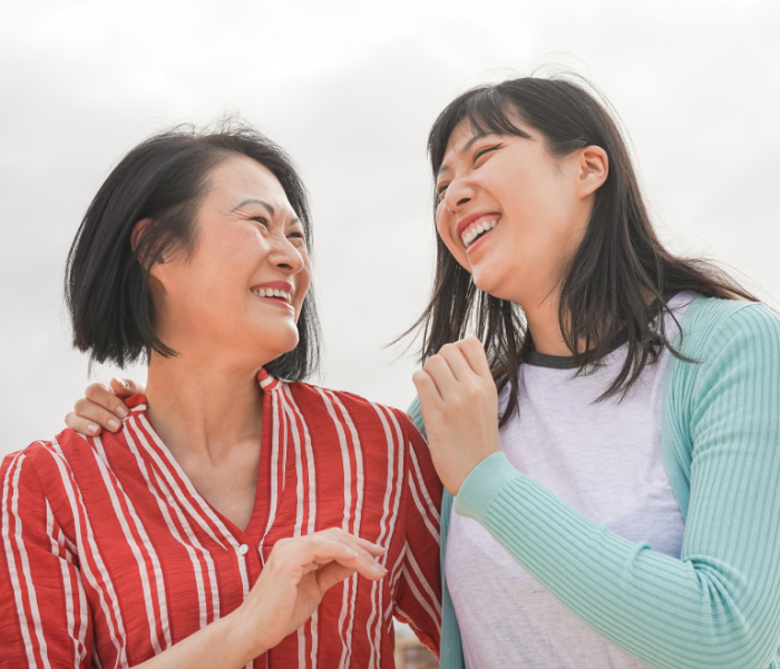 Two women smiling and laughing outdoors